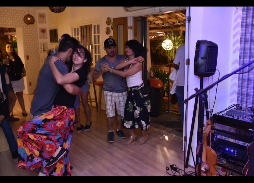 Casais dançando forró e samba no salão com luzes de festa